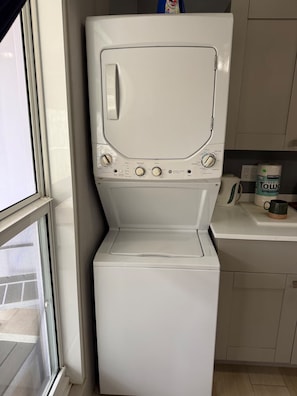 A front-loading white washer and dryer unit with control knobs and a small window on the top. - Relaxing Luxury Villa Private Beach Pool-Gym-AC-WiFi-King Bed-Sleeper Sofa (Turtle Bay)