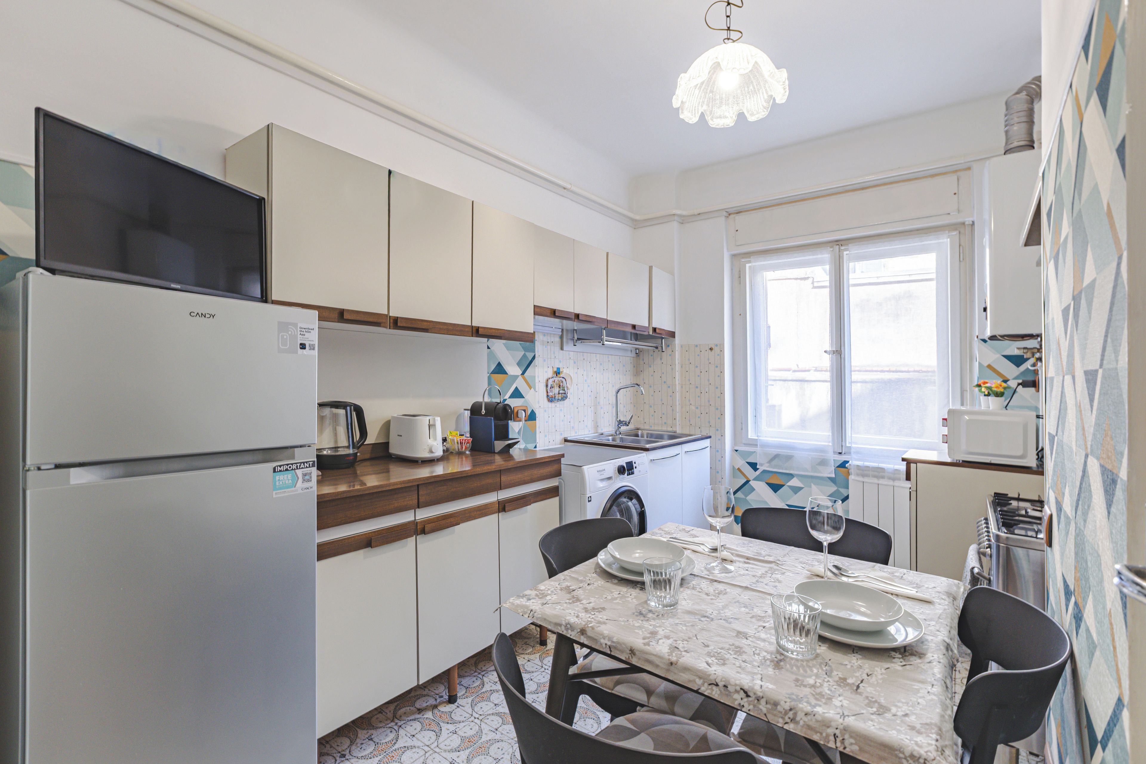A compact kitchen with a refrigerator, stove, and dining area with chairs and a table.