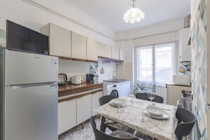 Una cocina compacta con refrigerador, estufa y comedor con sillas y una mesa.