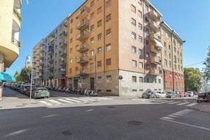 Un edificio residencial de varios pisos con balcones, un estacionamiento y vista a la calle.