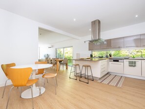 Een moderne keuken met een centraal eiland, roestvrijstalen apparatuur en uitzicht op groen door het raam.