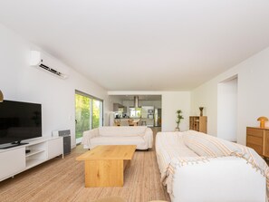 A modern living room with a TV, sofa, and dining area. - Hibiscus Bliss - Luxury villa V4 with private pool (Tavira)