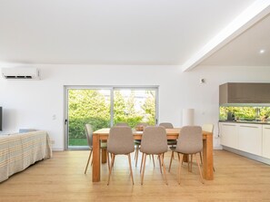 A modern kitchen with a dining area, a large window, and a flat-screen TV. - Hibiscus Bliss - Luxury villa V4 with private pool (Tavira)