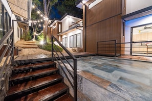 A modern outdoor area with a stone pool, wooden steps, and a metal railing.