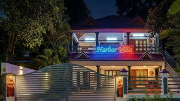 Un immeuble de deux étages, avec une enseigne au néon indiquant « Harbor Villa » à l’entrée.