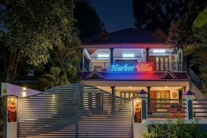 A two-story building with a neon sign reading 'Harbor Villa' at the entrance.