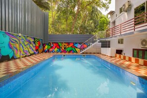 A swimming pool with a colorful mural on the adjacent wall, a staircase leading to an upper level, and a red railing. - Harbour villa, Vellayani Lake (Thiruvananthapuram)