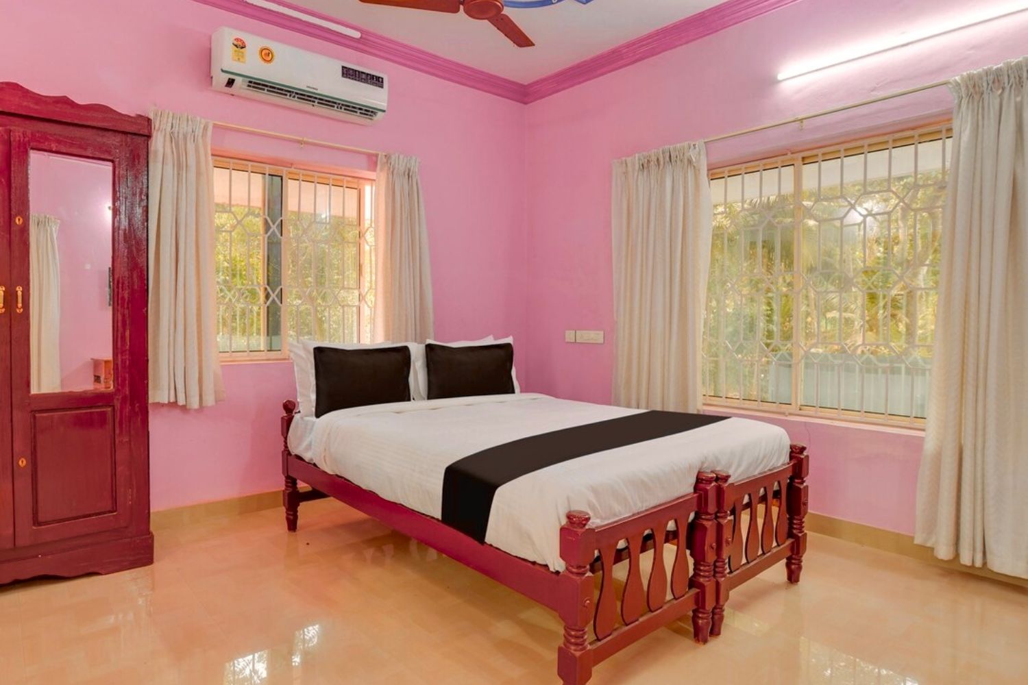 Un dormitorio con una cama de madera, paredes rosas y dos ventanas con cortinas.
