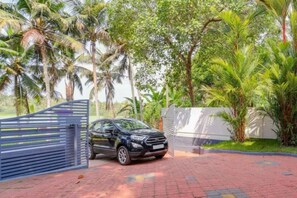 A black car parked in front of a gated entrance with a brick pathway leading to it.