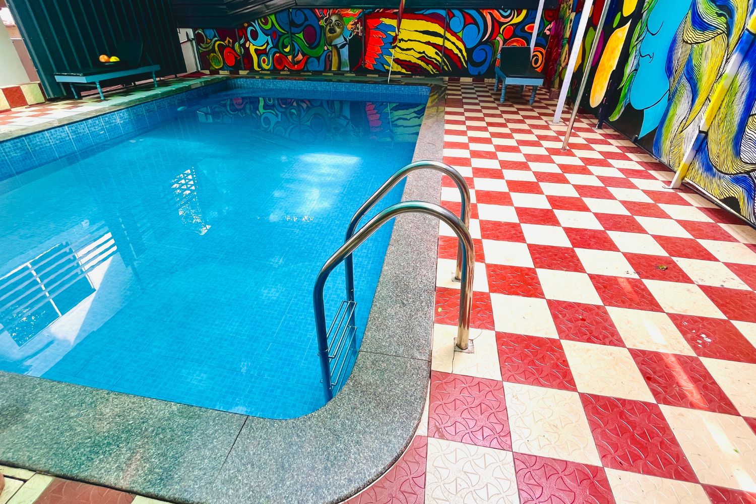 Una piscina con piso a cuadros y barandillas metálicas.