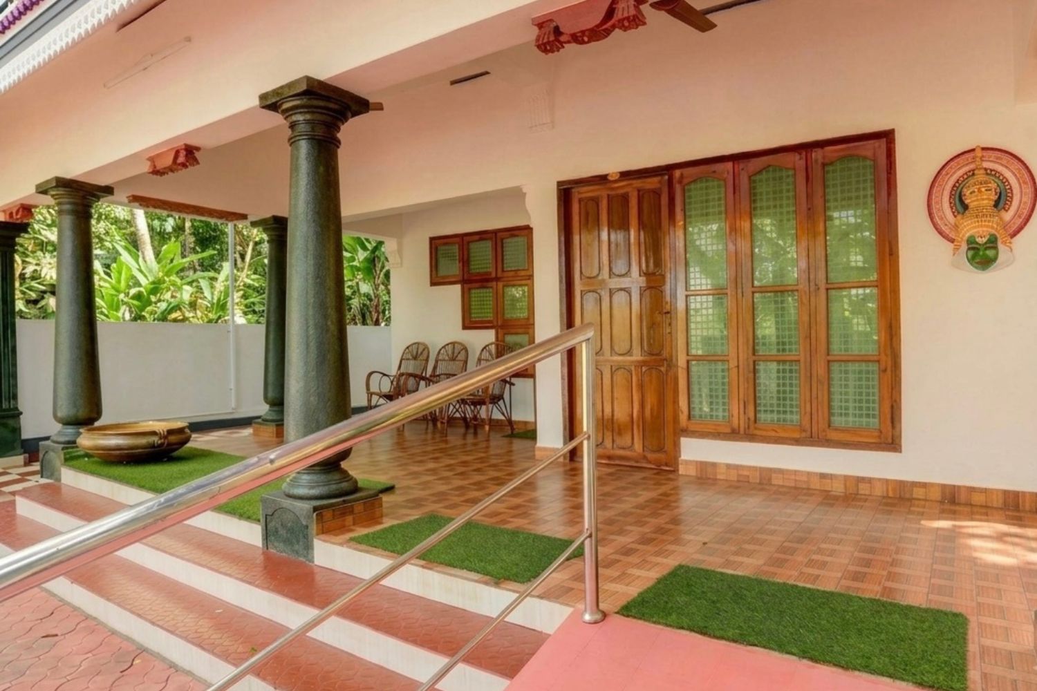 Un espacio al aire libre cubierto con escaleras, columnas y una puerta con paneles de vidrio.