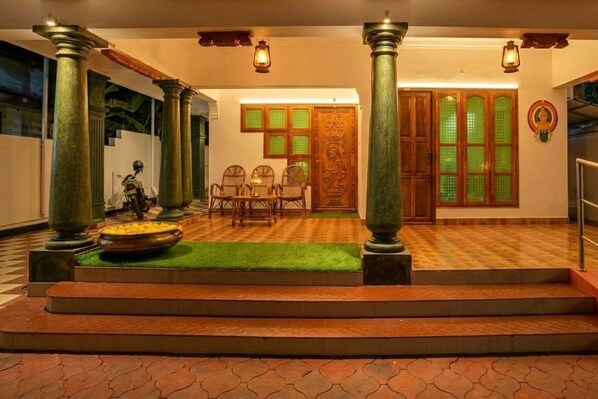 A traditional interior with columns, a checkered floor, and a dining area with chairs and a table.