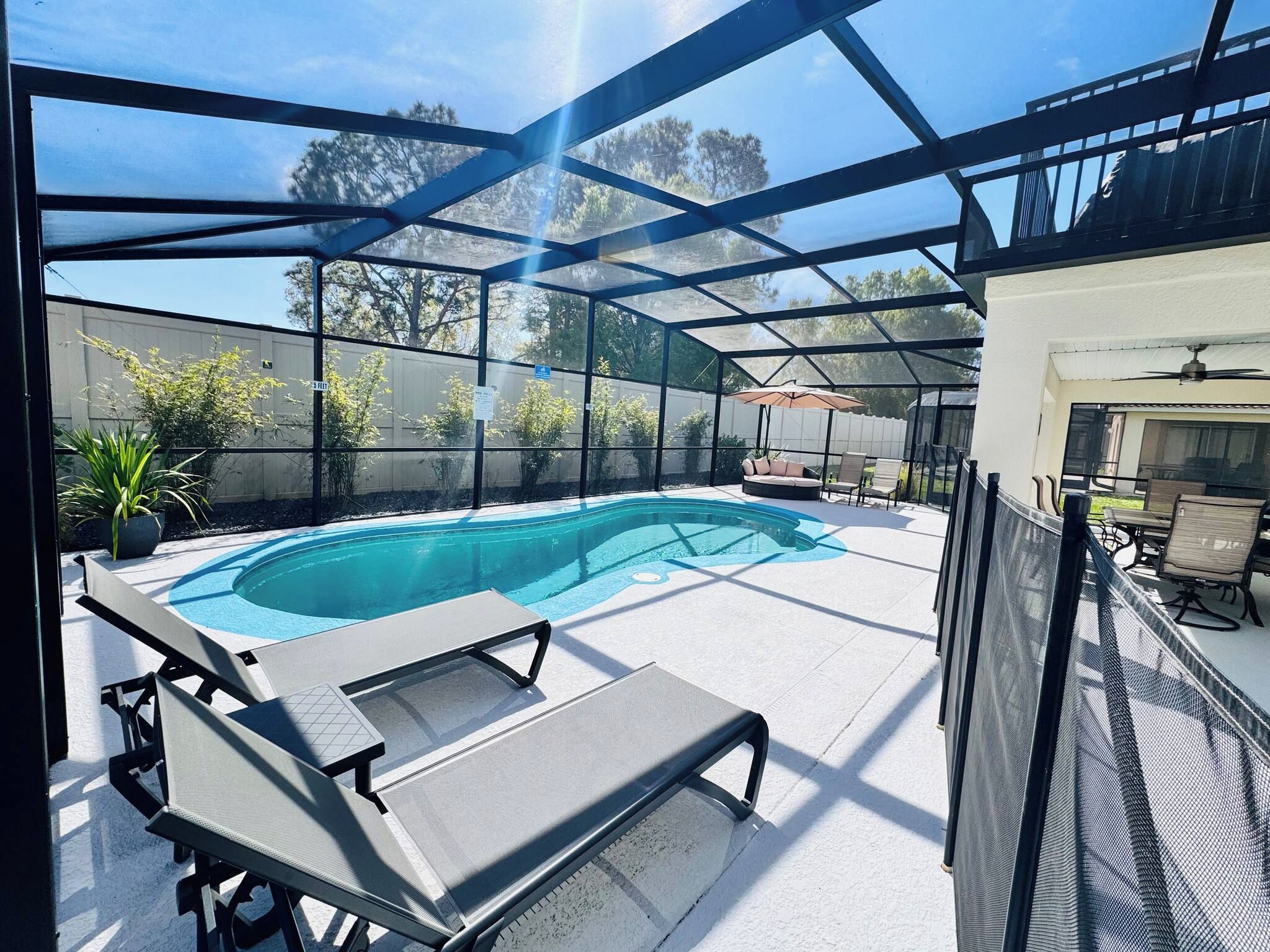 Une piscine extérieure couverte, dotée de chaises longues et d’un espace patio.