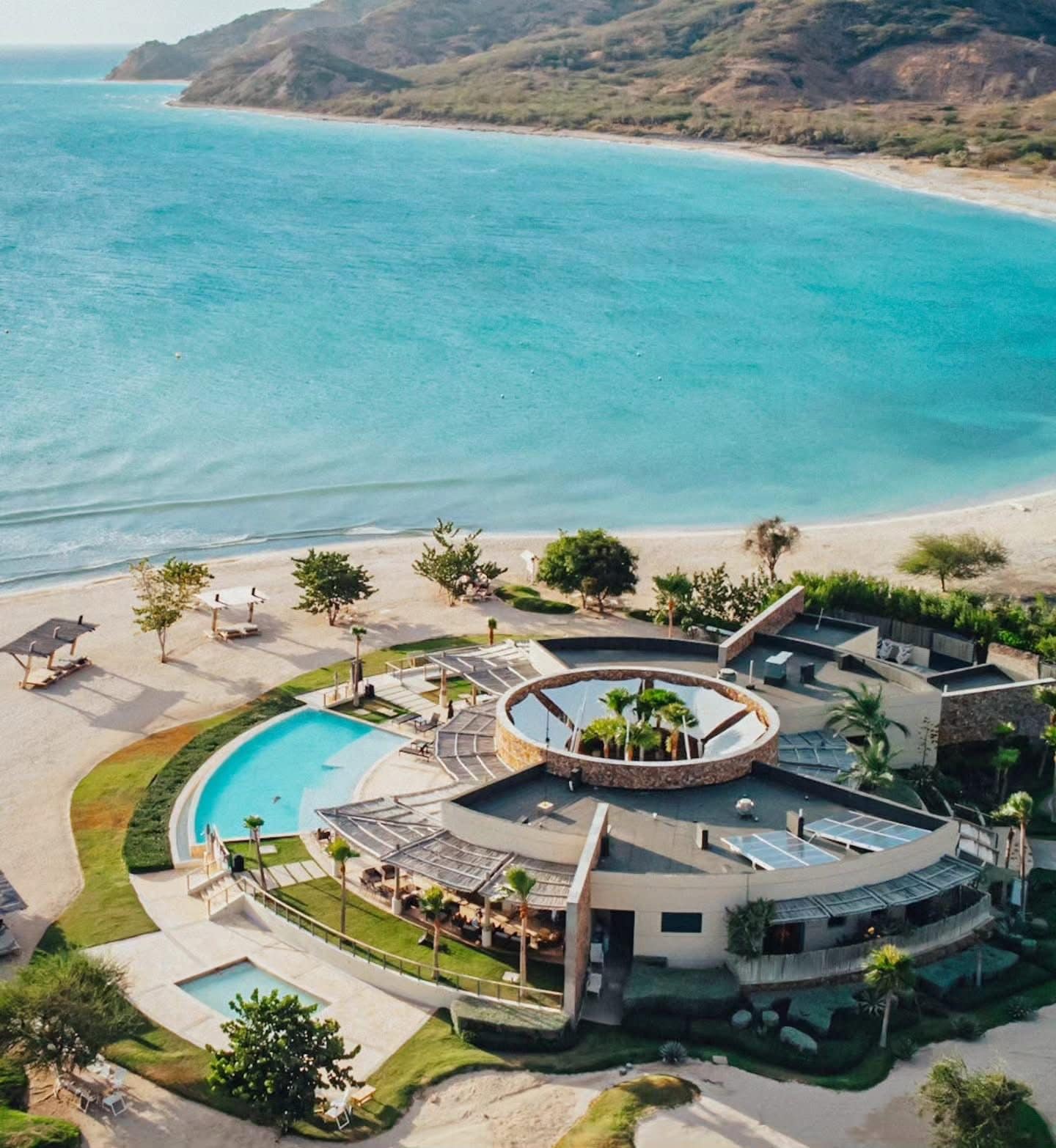 Ein Resort mit einem zentralen Pool, Liegestühlen und Blick auf den Ozean.
