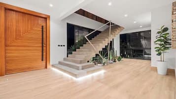 Ein modernes Interieur mit einer Holztür, einer Treppe mit geometrischer Geländer und einem Blumentopf.