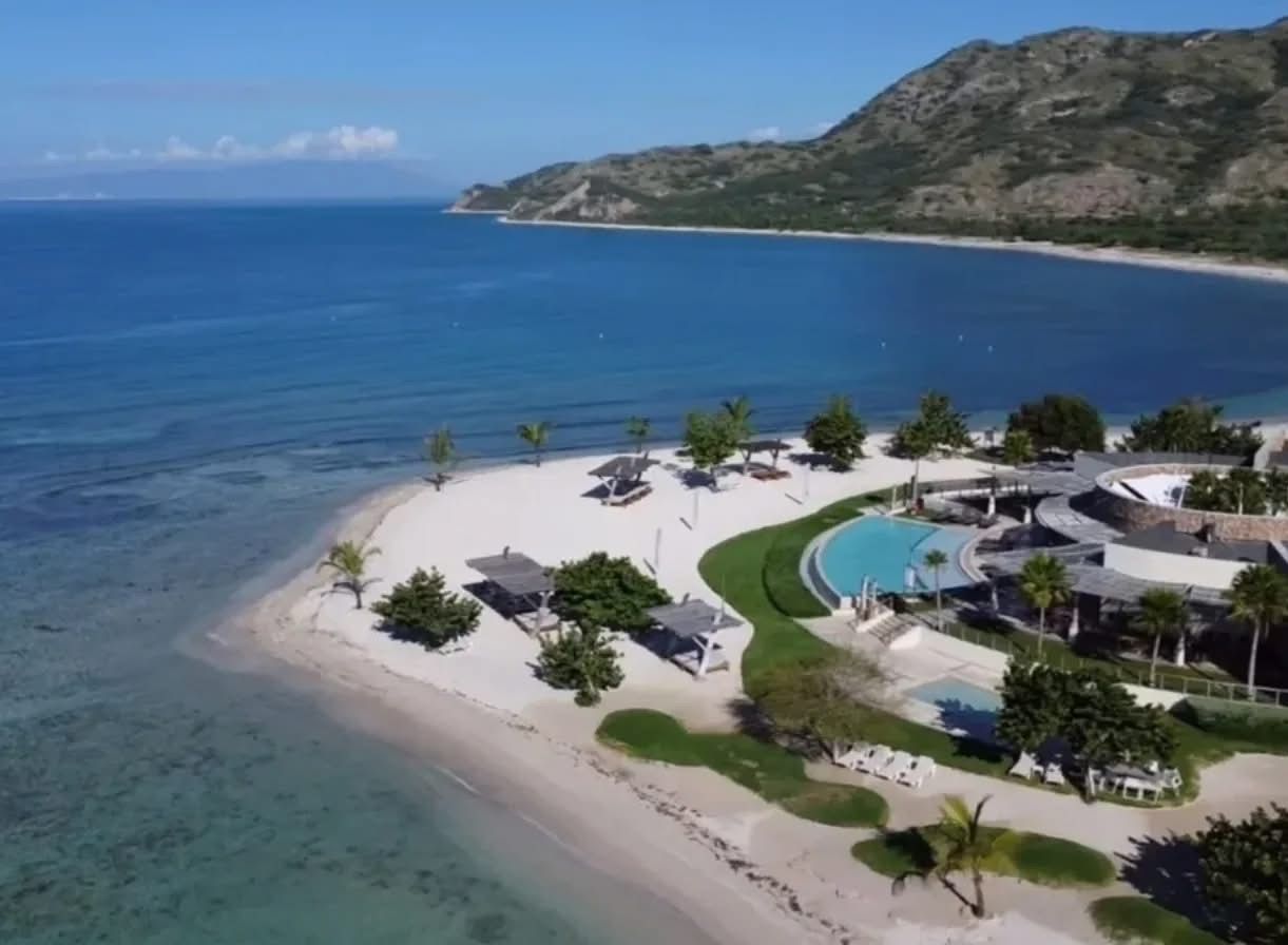 Ein Küstenresort mit Strand, Pool und einer Bergkulisse.