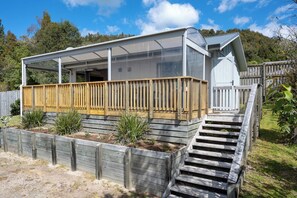 Een modern huis met een overdekte veranda, een houten terras en een trap naar de ingang.