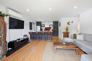 Een moderne woonkamer met een flatscreen televisie, een houten salontafel en een grijze bank.