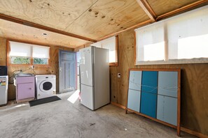 A compact kitchen with a refrigerator, washing machine, and a sink. - Whangaroa Landing - Lake Rotoma Holiday Home (Rotorua)