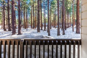 A forested area with tall trees and a snow-covered ground, viewed from a wooden railing. - Pet Friendly Mammoth Studio w/ self check in (Mammoth Lakes)