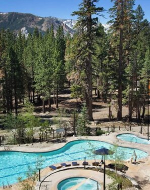 A pool area with multiple swimming pools surrounded by trees and mountains in the background. - Pet Friendly Luxury Mammoth Westin Condo (Mammoth Lakes)