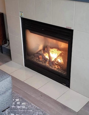 A fireplace with a visible fire, a caution sign, and a cable running along the wall. - Pet Friendly Luxury Mammoth Westin Condo (Mammoth Lakes)