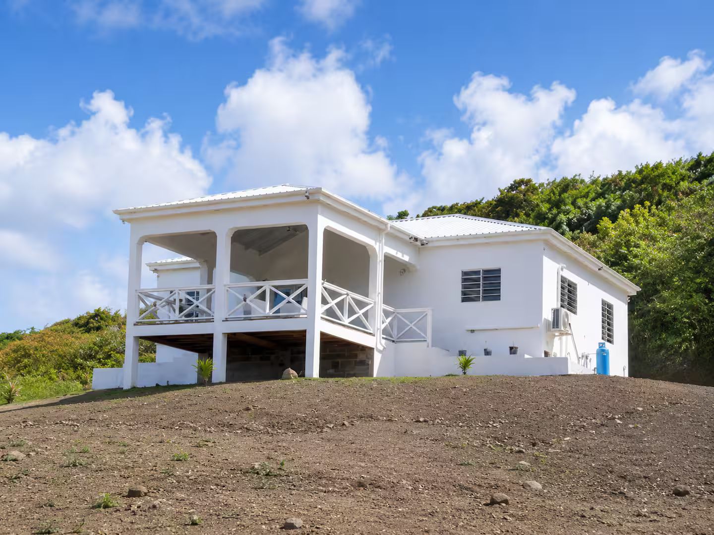 A white building with a covered porch and a small garden area.
