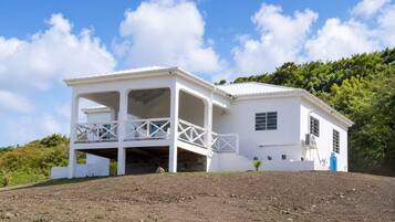 A white building with a covered porch and a small garden area.