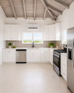 Una cuina moderna amb armaris blancs, un rentaplats d'acer inoxidable, una cuina a gas i un forn integrat.