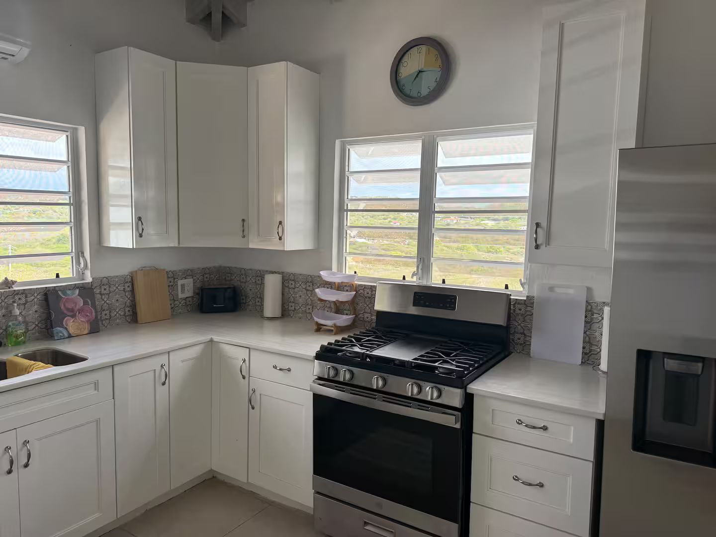 Une cuisine avec des meubles blancs, une cuisinière, un évier et une fenêtre donnant sur un beau paysage.