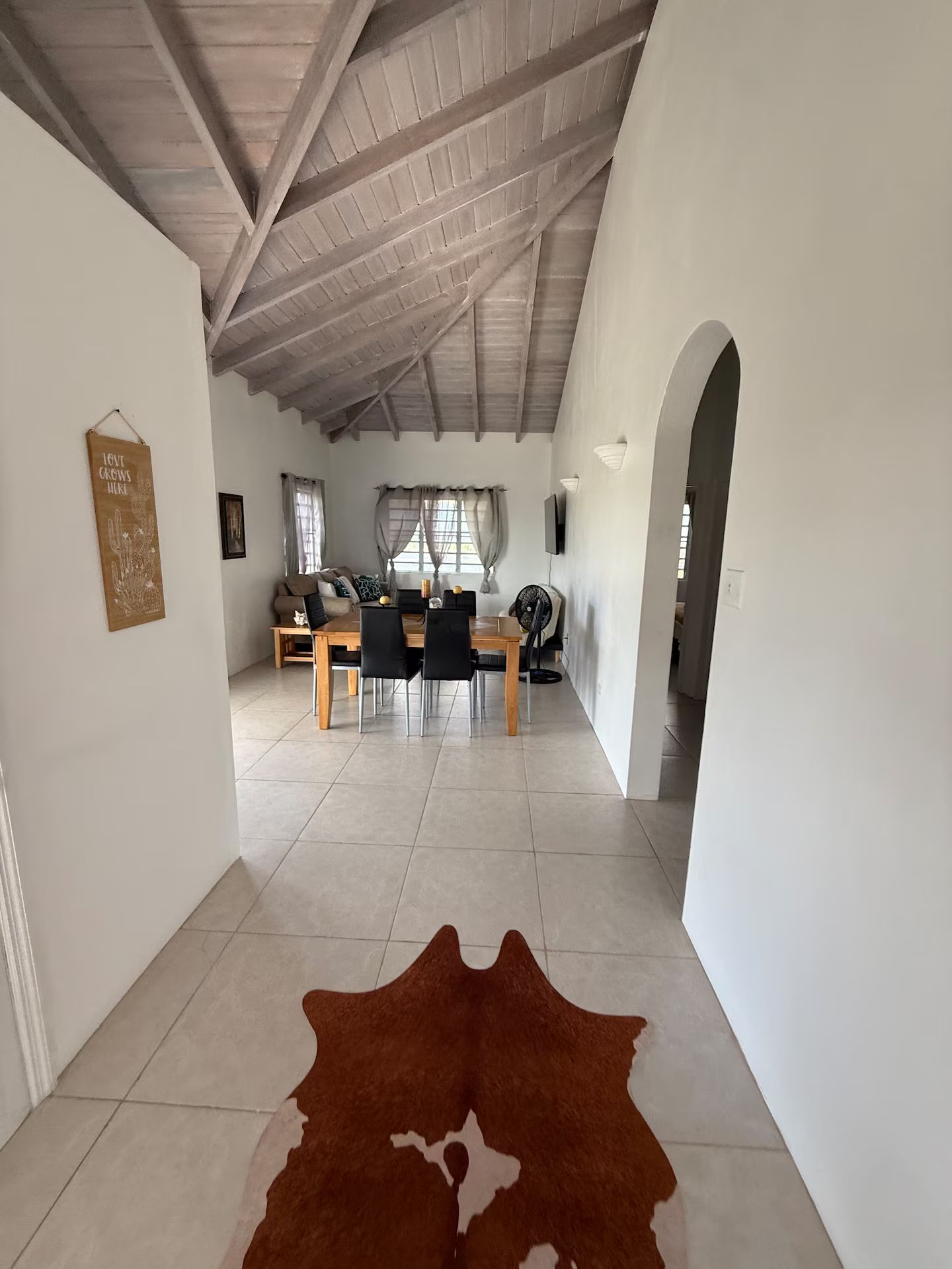 Un vaste espace de vie doté d’un plafond haut, d’une table à manger avec des chaises et d’un tapis en peau de vache sur le sol.