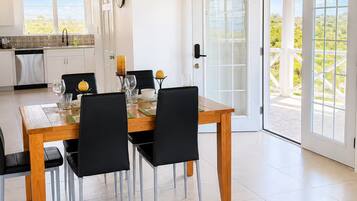Un comedor con una mesa y sillas de madera, una cocina al fondo y vistas a través de un ventanal.