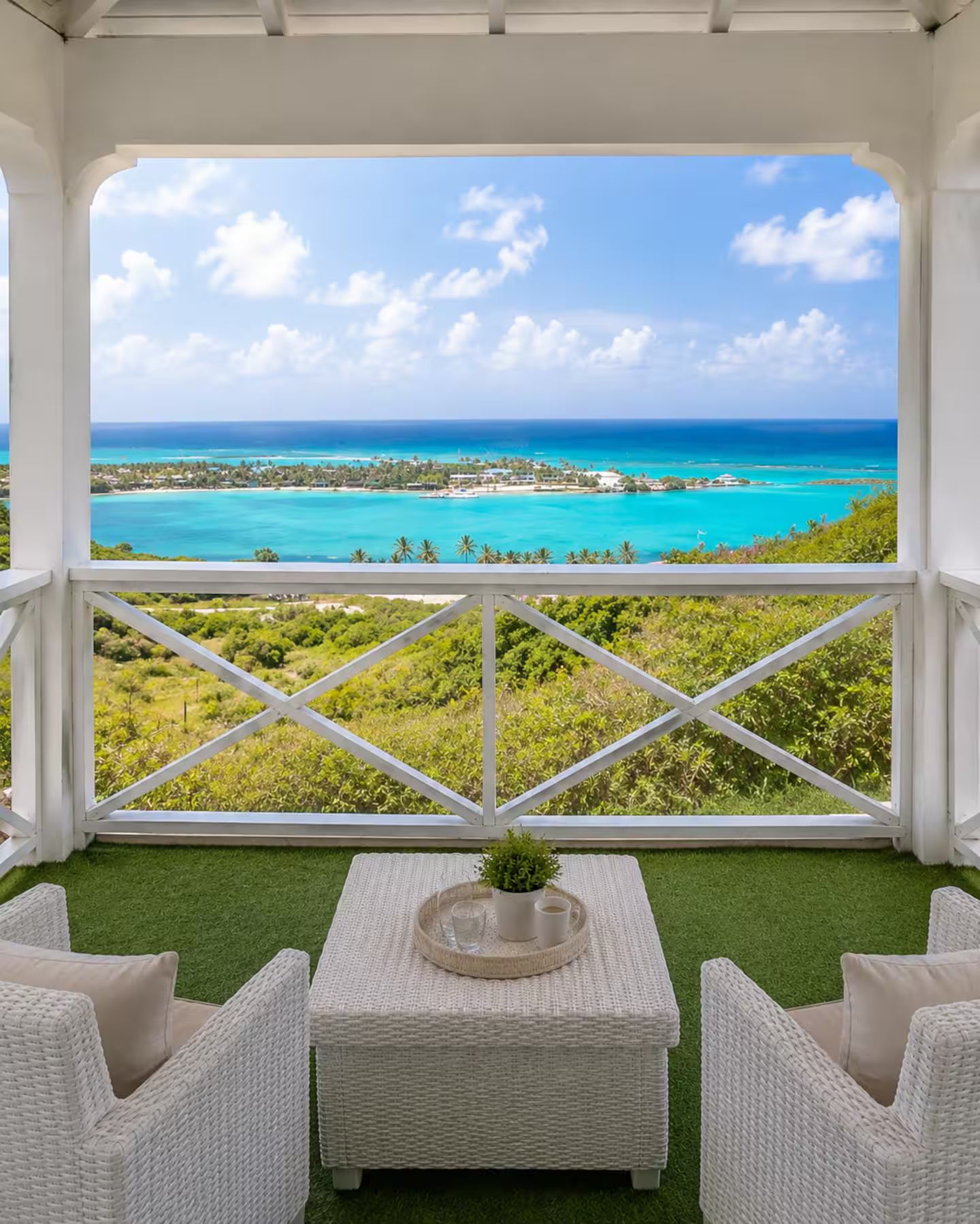 Un espace extérieur abrité, aménagé avec des sièges, offrant une vue sur une mer turquoise et un ciel dégagé.