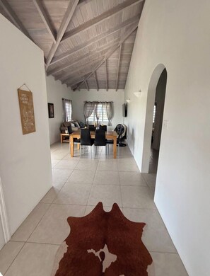A spacious living area with a high ceiling, a dining table, and a sofa.