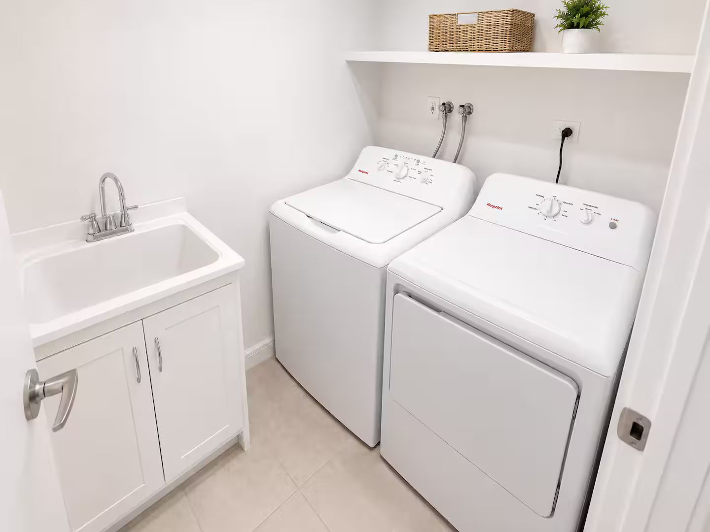 A laundry area with two white washing machines, a sink, and a cabinet.