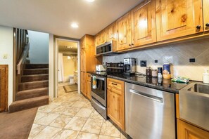A kitchen with wooden cabinets, stainless steel appliances, and a tiled backsplash. - Mammoth Home-Away-From-Home (Mammoth Lakes)