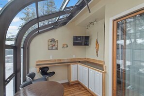 A compact kitchen with a wooden countertop, white cabinets, a round table, and a TV mounted on the wall. - Pet Friendly Classic Mammoth Cabin (Mammoth Lakes)