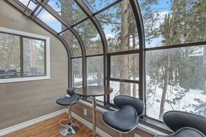 Een modern interieur met een gebogen glazen wand, houten vloer en een ronde tafel met stoelen.
