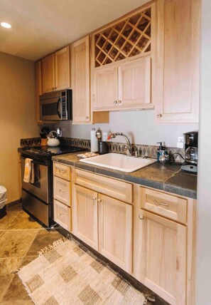 A kitchen with wooden cabinets, a stainless steel oven, a microwave, and a sink. - Mammoth’s Modern Studio w/ Self Check in (Mammoth Lakes)