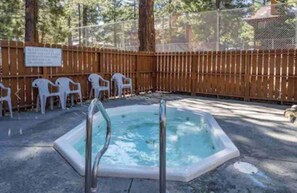 A hot tub surrounded by a wooden fence, with a sign on the fence and white plastic chairs in the background. - Mammoth’s Modern Studio w/ Self Check in (Mammoth Lakes)