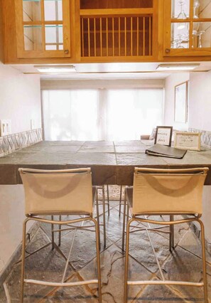 A kitchen with a stone countertop, two metal chairs, and wooden cabinets. - Mammoth’s Modern Studio w/ Self Check in (Mammoth Lakes)