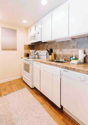 A modern kitchen with white cabinets, a microwave, stove, and dishwasher. - Charming Village Studio Loft (Mammoth Lakes)