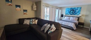 A living room with a sofa and a bed with a large floral artwork above it. - Modern Pet friendly Studio with bunks (Mammoth Lakes)