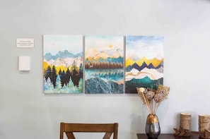 Een muur met drie schilderijen van berglandschappen.