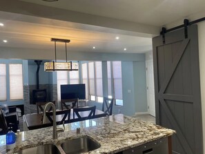 A modern kitchen with a granite countertop, stainless steel sink, and a sliding barn door. - Luxury Mammoth 2BR 2BA Townhome (Mammoth Lakes)