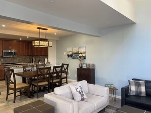 A modern living room with a sofa, a coffee table, and a dining area with chairs and a table. - Luxury Mammoth 2BR 2BA Townhome (Mammoth Lakes)