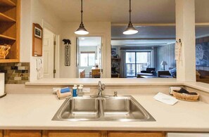 A kitchen with a double sink, wooden cabinets, and pendant lighting. - Slope Side Pet Friendly 1Bd Summit Condo (Mammoth Lakes)