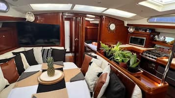 A yacht interior with a dining area, a kitchen, and a seating area with a view of the sea.