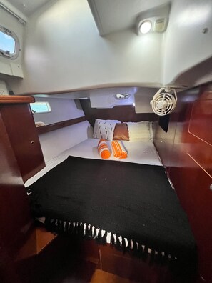 A compact cabin with a bed, pillows, and a small fan.