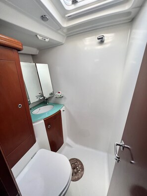 Et lille badeværelse med toilet, håndvask og brusebad.